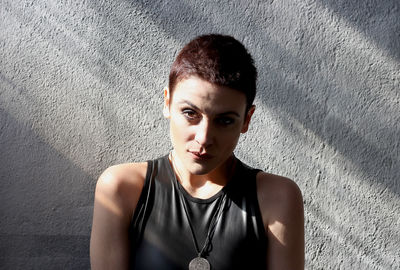 Portrait of beautiful young woman standing against wall