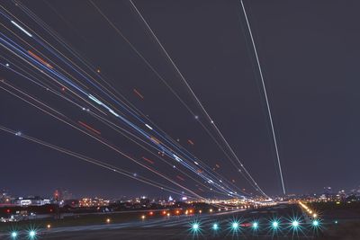 Low angle view of illuminated light trails on road against sky at night