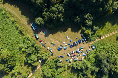 Aerial drone view of outdoor camp with tents and cars in a forest meadow