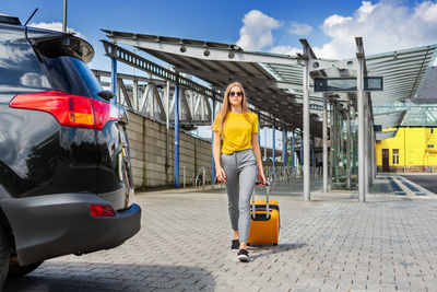 Full length of woman walking with luggage on footpath