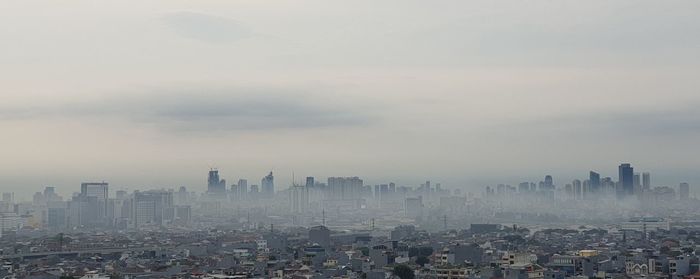 Aerial view of buildings in city against sky