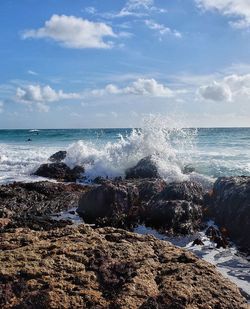 Waves splashing on sea against sky