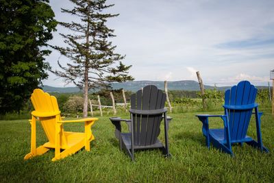 Empty chairs on field against sky