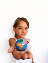 Portrait of girl holding globe against white background