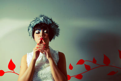 Portrait of woman holding red umbrella against wall