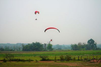 Hot air balloon flying over field against sky