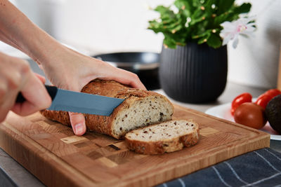 Woman cutting loaf of bread with large knife