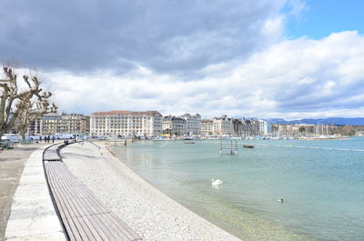 View of buildings by sea against cloudy sky