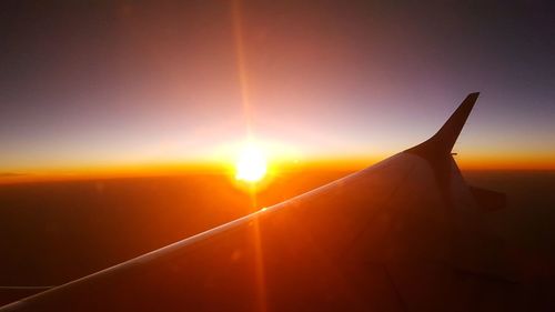 Close-up of airplane wing against sky during sunset