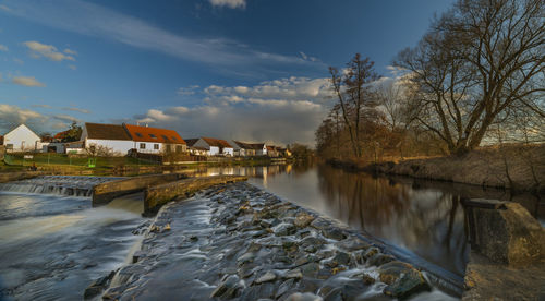 Scenic view of river by buildings against sky
