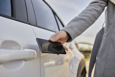 Woman unlocking electric car through smart phone