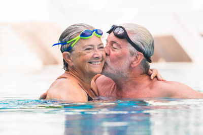 Senior man kissing woman in swimming pool