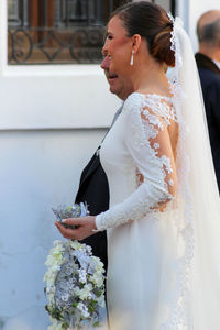 Close-up of woman wearing dress standing against wall