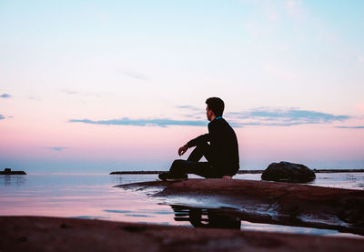 Silhouette man looking at sea against sky during sunset