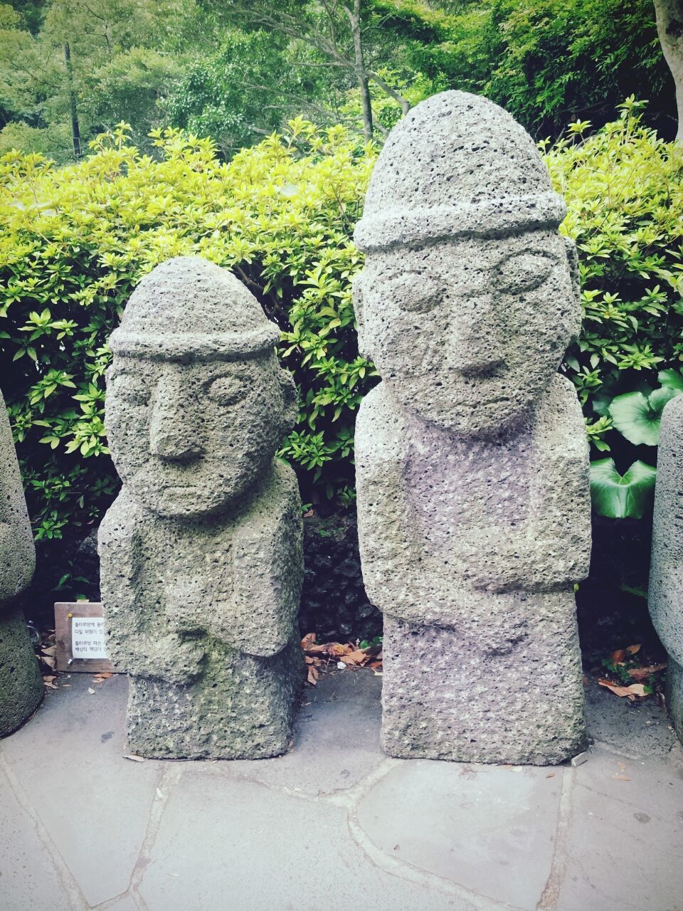 human representation, sculpture, statue, art, art and craft, creativity, stone material, green color, park - man made space, tree, formal garden, stone - object, growth, plant, outdoors, day, stone, religion