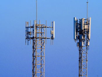 Low angle view of communications tower against clear blue sky