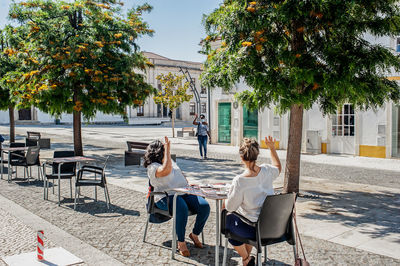 Woman waving to female friends sitting at cafe