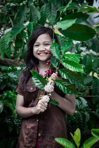 Young woman smiling while holding plant