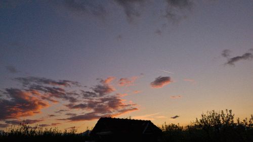 Silhouette trees and buildings against sky at sunset