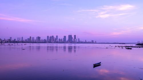 Scenic view of sea and buildings against sky during sunset