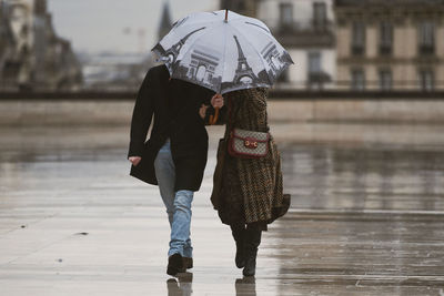 Rear view of woman with umbrella walking in rain