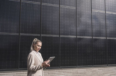 Businesswoman using tablet pc in front of solar panels