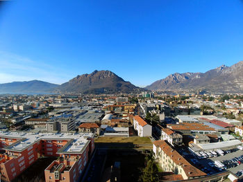 Townscape by mountains against clear blue sky