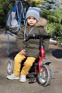 Portrait of cute boy sitting on tricycle on footpath