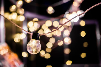 Close-up of illuminated light bulb against defocused lights