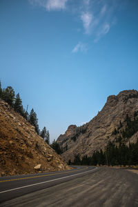 Road by mountains against blue sky