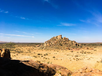 Rock formations on landscape against blue sky