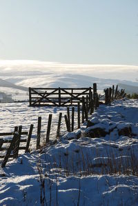 Wooden posts on frozen sea against clear sky