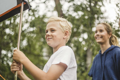 Smiling boy looking away while standing by tent at campsite