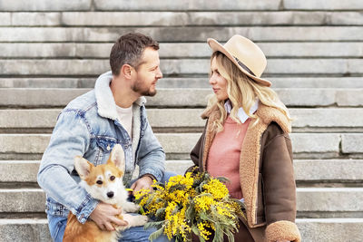 A couple in love on a date. a blonde in a hat and a man look at each other. walking with corgi dogs