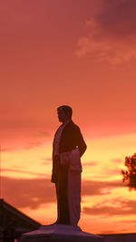 Low angle view of silhouette man against orange sky