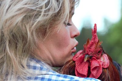 Beautiful woman in the farm holding a chicken, healthy lifestyle