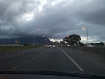 Road against cloudy sky seen through car windshield