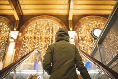 Rear view of woman walking in illuminated train station 