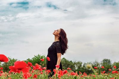 Full length of young woman standing on field against sky