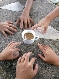 Cropped hands of friends reaching for coffee on footpath