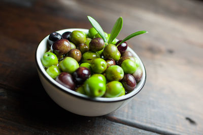 Close-up of olives in bowl on wooden table