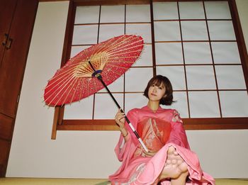 Young woman sitting with umbrella