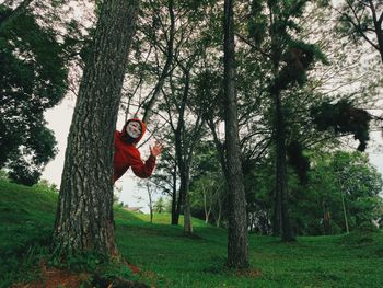 Person wearing mask gesturing by tree