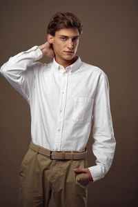 Portrait of young man standing against brown background