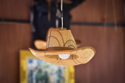 Close-up of hat hanging on wood at home