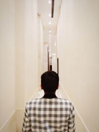 Rear view of man walking in illuminated building