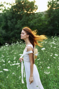 Young woman standing against plants