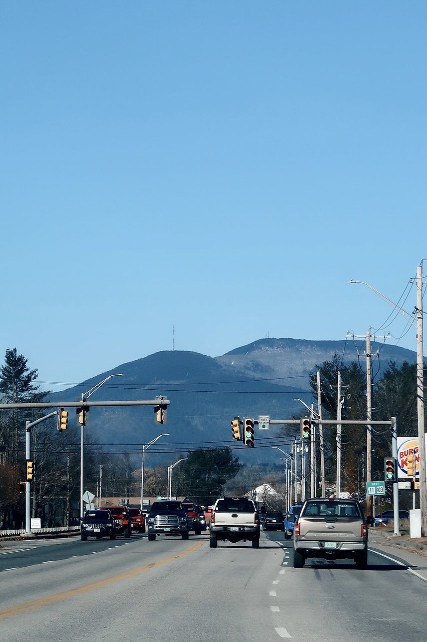 ROAD BY CITY AGAINST CLEAR BLUE SKY