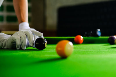 Cropped hand of man playing pool ball
