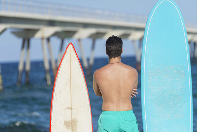 Rear view of shirtless man standing at beach